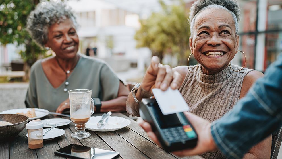 Two elderly women paying with a credit card.