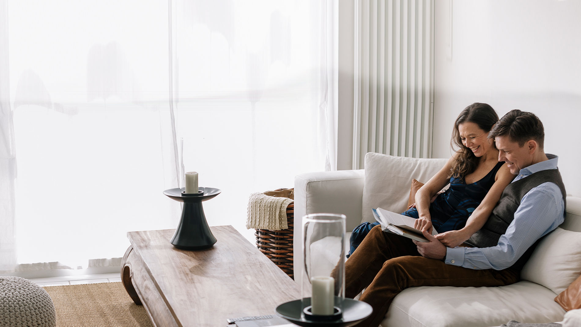 Couple sitting on couch together looking through a book.