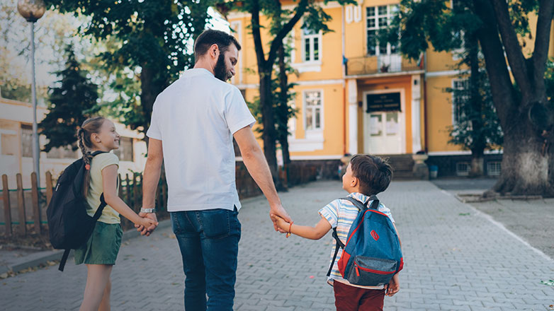 Dad walking his son and daughter into their new school on their first day.