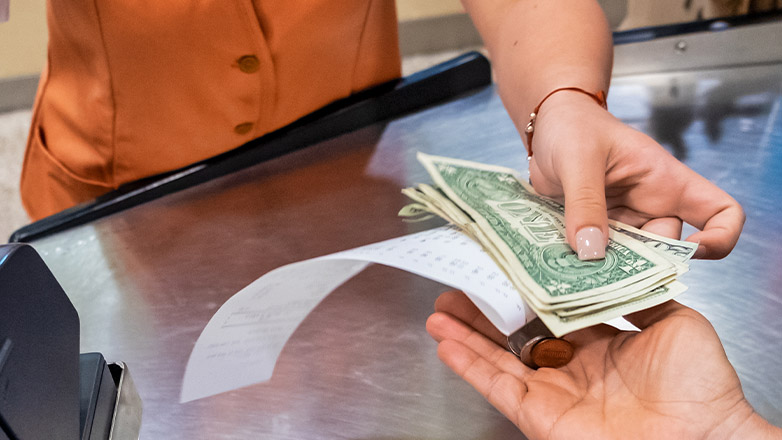 business owner handing back dollars and coins to customer with a receipt.