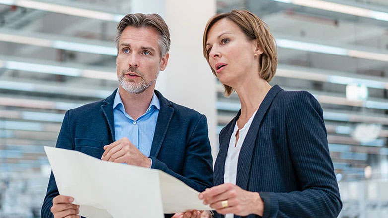 Two business owners review the layout plans for their new warehouse.