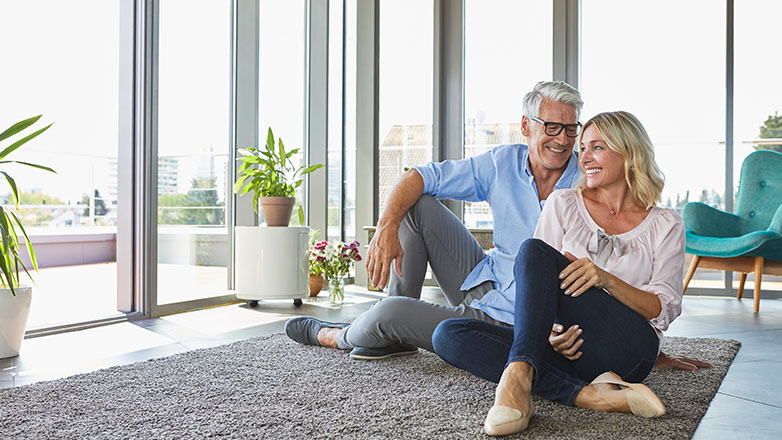 Couple sitting on their living room floor looking out the window.