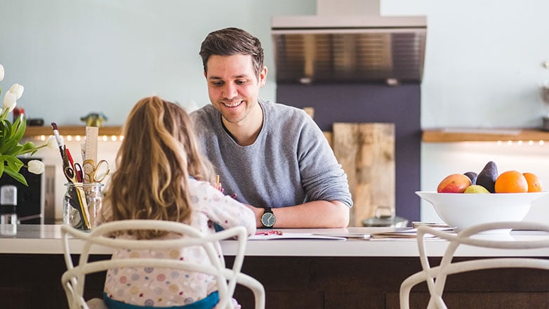 Dad helping his young daughter do her homework at the kitchen island.