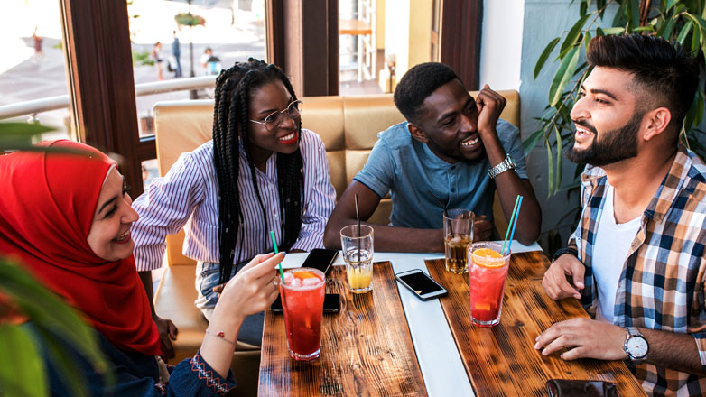 group of friends hanging out on a couch enjoying drinks and laughing.