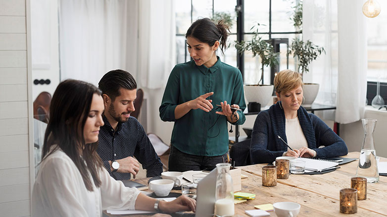 Group meeting with female  manager giving direction to her associates.