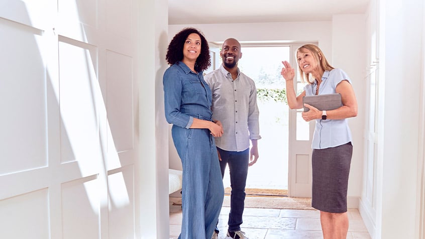 realtor showing young couple a new house.