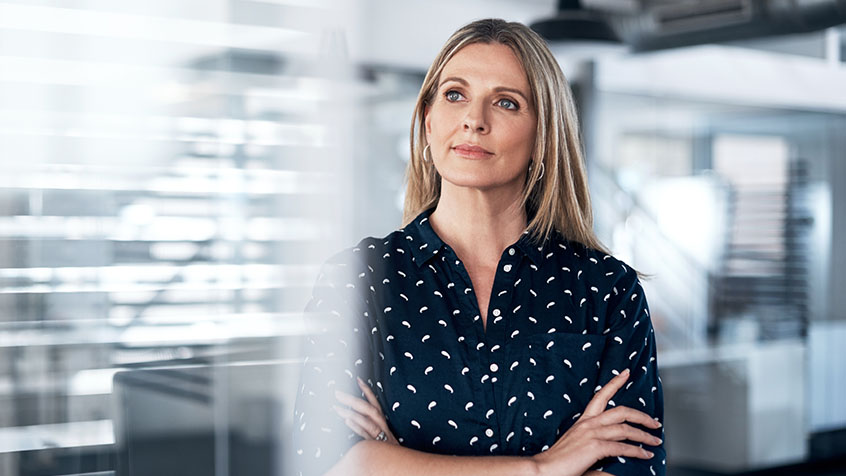 woman gazing out the window in deep thought in an office setting.