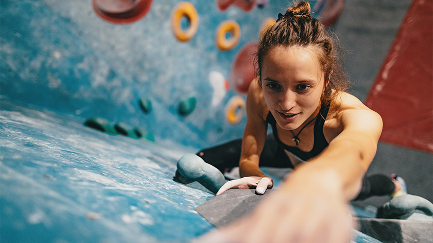 young woman rock climbing up a rockwall.