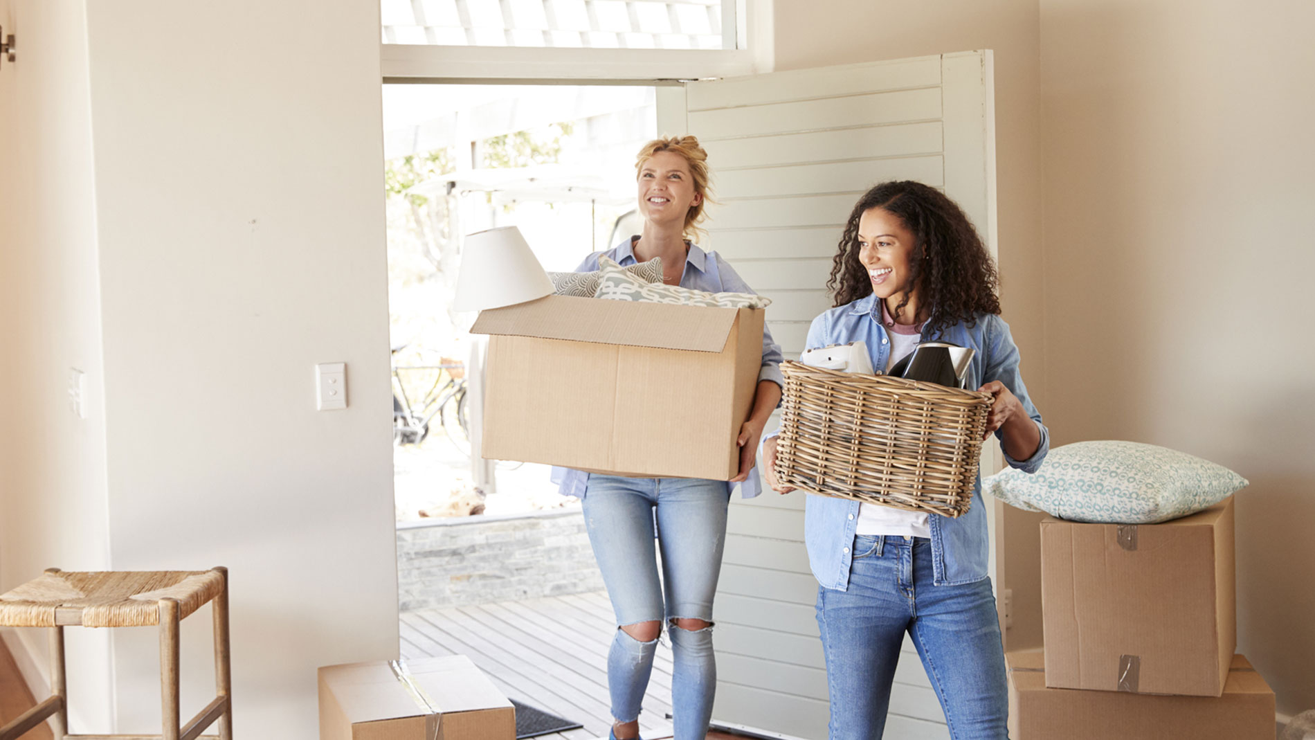 two women carrying boxes into new home