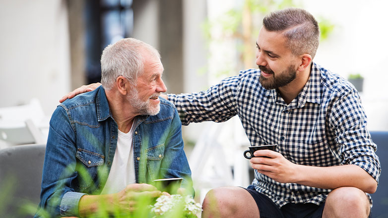 father and son sitting outside drinking coffee