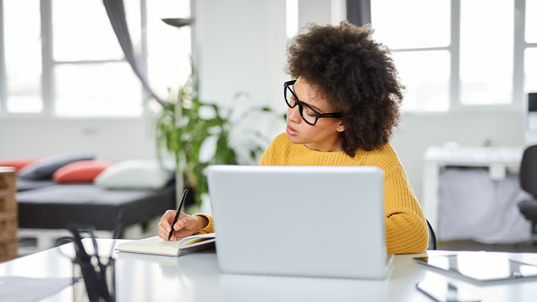 Woman sitting with laptop and marking things off checklist