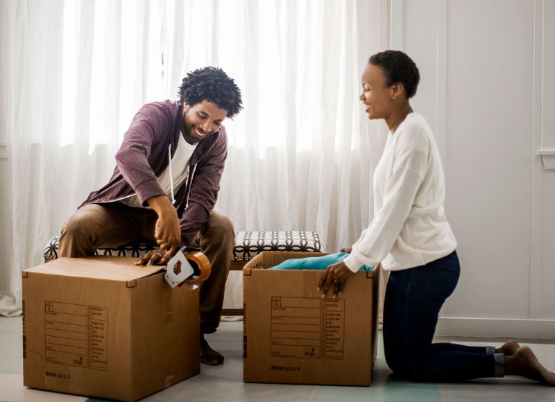 A couple unpacks boxes in the living room of their old home.