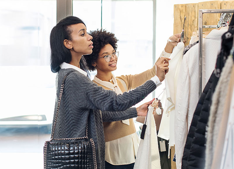 Two female friends shop together for clothes.