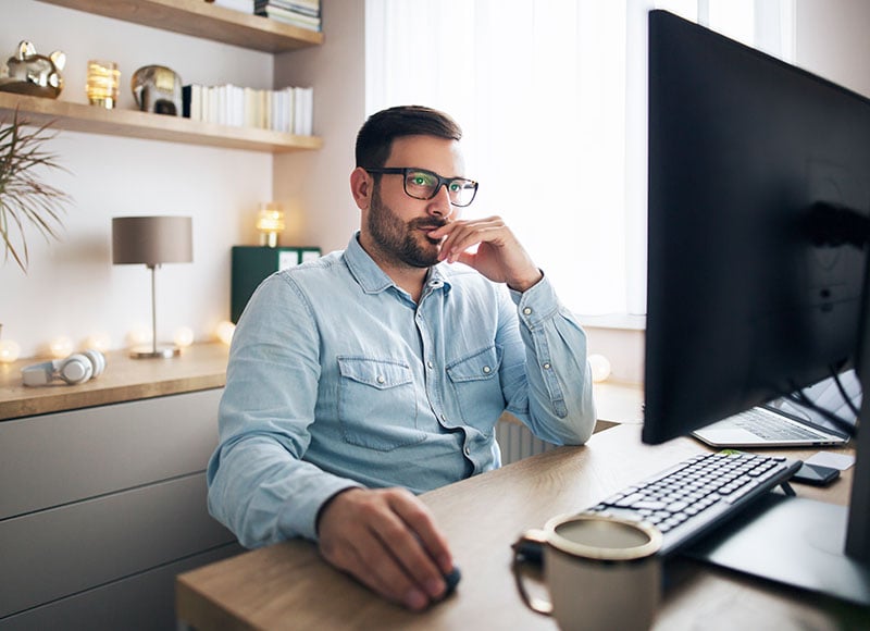 A man works on his computer from his home office.